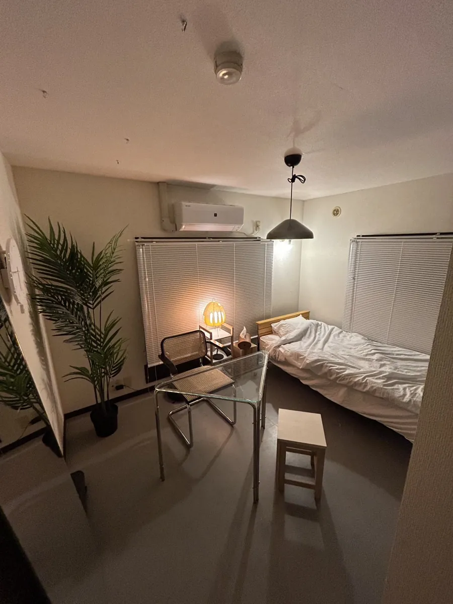 ベッドとデスク、観葉植物を備えたMOOOM HOUSEの個室